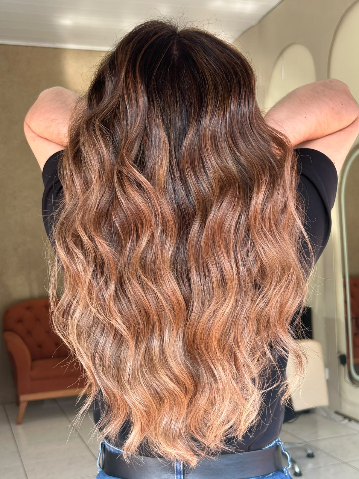 Morena iluminada com ondas longas e mechas acobreadas